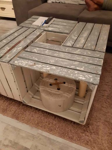 Holztisch mit mehreren Fächern, darunter ein zylindrischer Behälter.