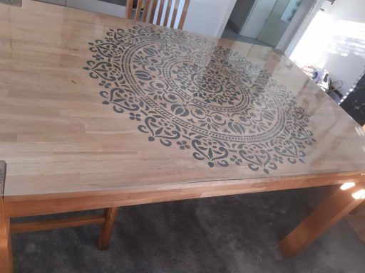 Holztisch mit kunstvollem, dunkel gefärbtem Mandala-Muster in der Mitte.