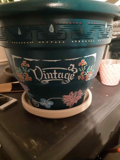 Blauer Blumentopf mit dem Aufdruck "Vintage" und floralen Verzierungen.
