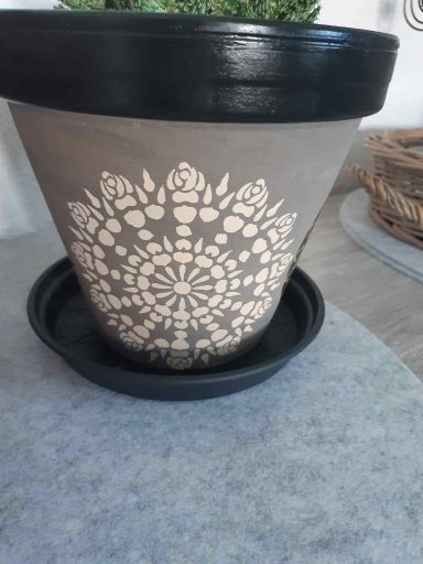 Blumentopf mit filigranem, hellen Mandala-Muster und schwarzem Rand auf Untersetzer.