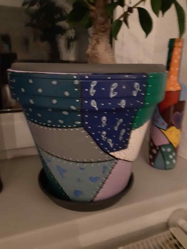 Bunter Blumentopf mit geometrischen Mustern und einer ähnlichen dekorativen Vase im Hintergrund.