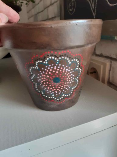 Brauner Blumentopf mit buntem Mandala-Muster in Rot, Weiß und Blau.