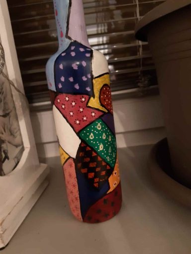 Bunte, kunstvoll bemalte Flasche mit geometrischen Mustern und leuchtenden Farben.