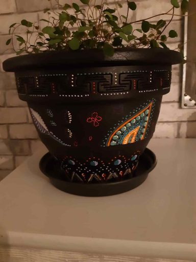 Bunter Blumentopf mit dekorativen Mustern und einer Untertasse.