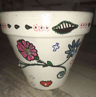 Blumentopf mit bunten, handgemalten Blumen und dekorativen Mustern.