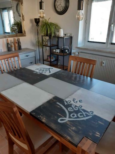 Ein Esszimmer mit hölzernem Tisch, Stühlen und Dekorationselementen im Hintergrund.