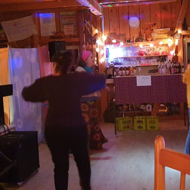 Licht-im-ich.de Person tanzt in einem lebhaften Raum mit bunten Lichtern und festlicher Atmosphäre.
