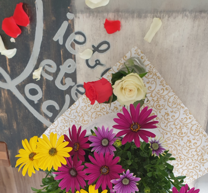 Bunte Blumenarrangements mit Rosen, Gänseblümchen und Blütenblättern auf einem Tisch.