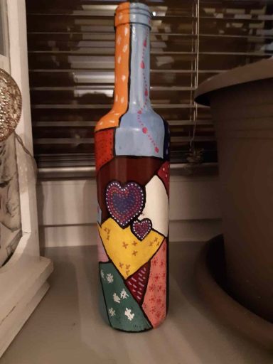 Bunte, künstlerisch gestaltete Flasche mit Herz- und Mustermotiven auf dem Glas.